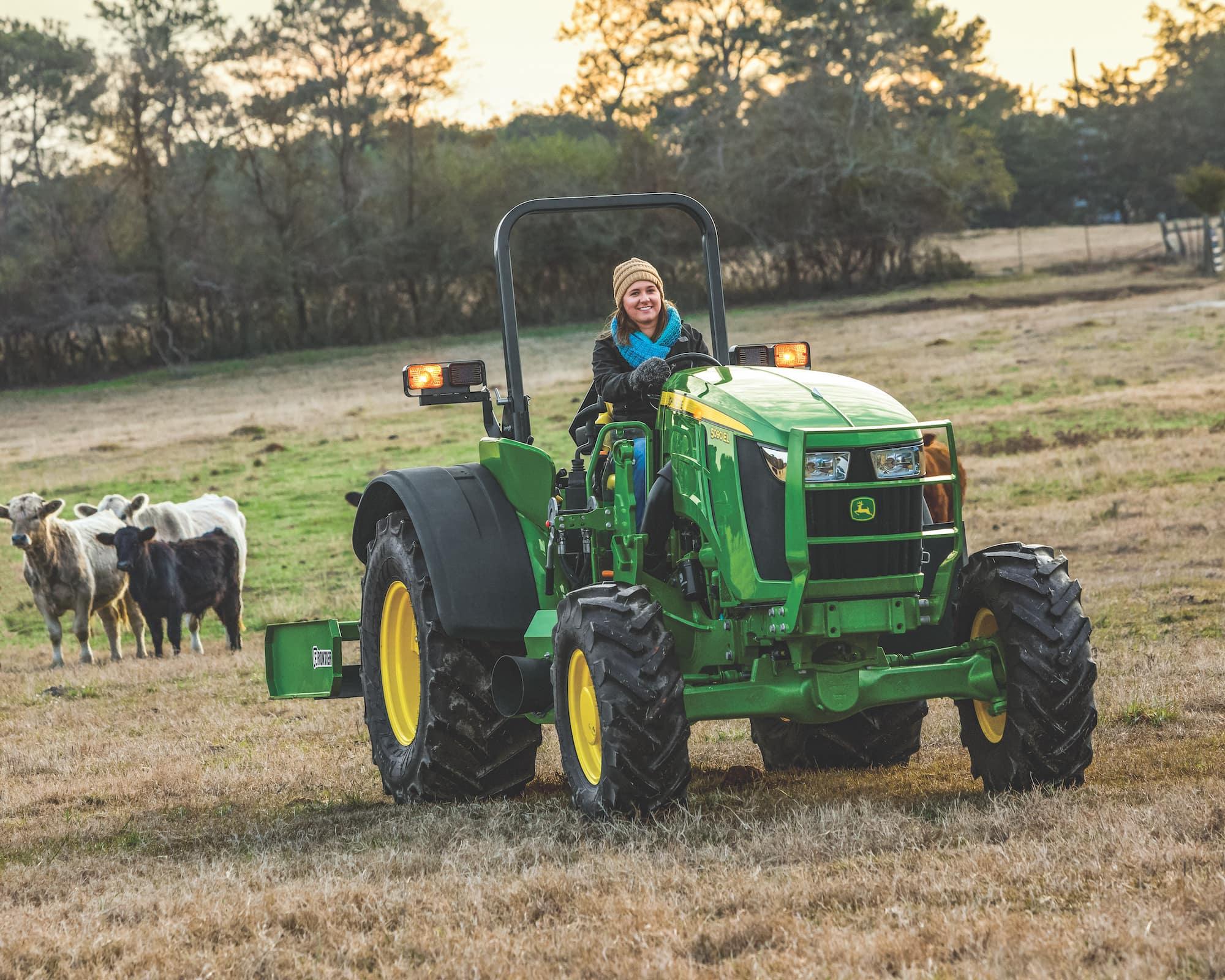 happy farmer passing three cows on their tractor